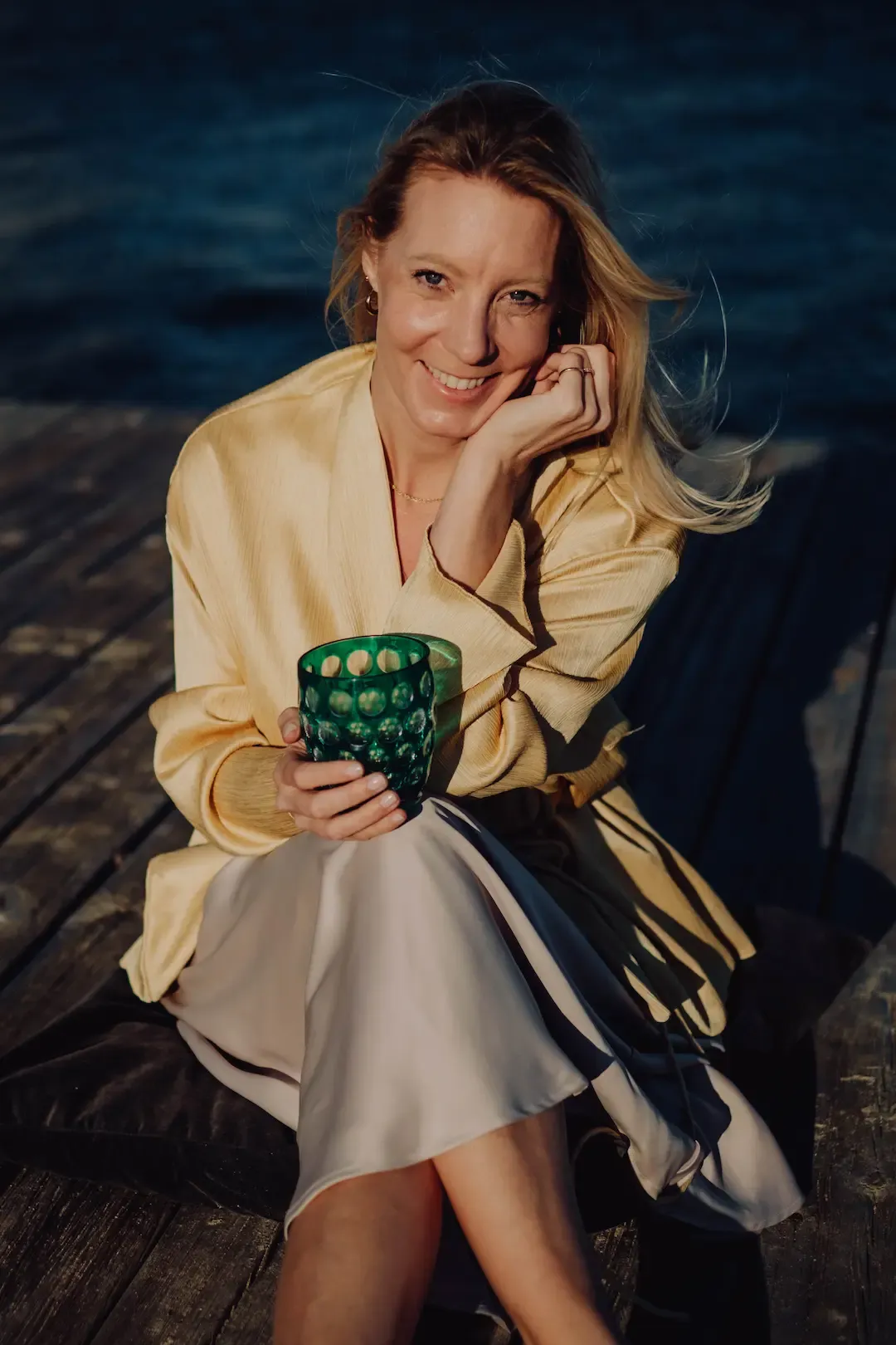 Nadine Kleifges sitzt lächelnd auf einem Steg am Wasser